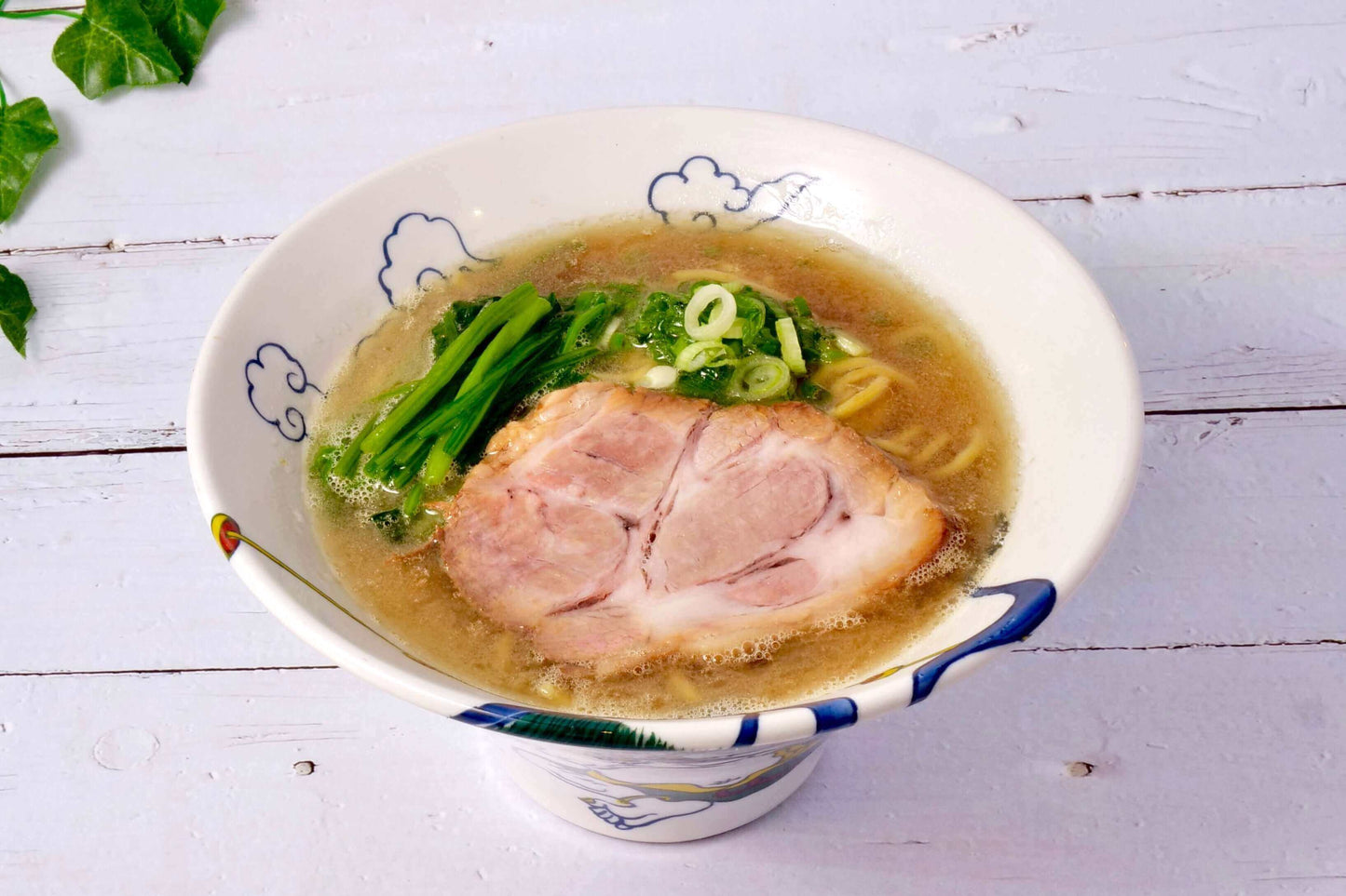 Iekei ramen preparation guide with rich broth, sliced pork, and green vegetables in a decorative bowl.